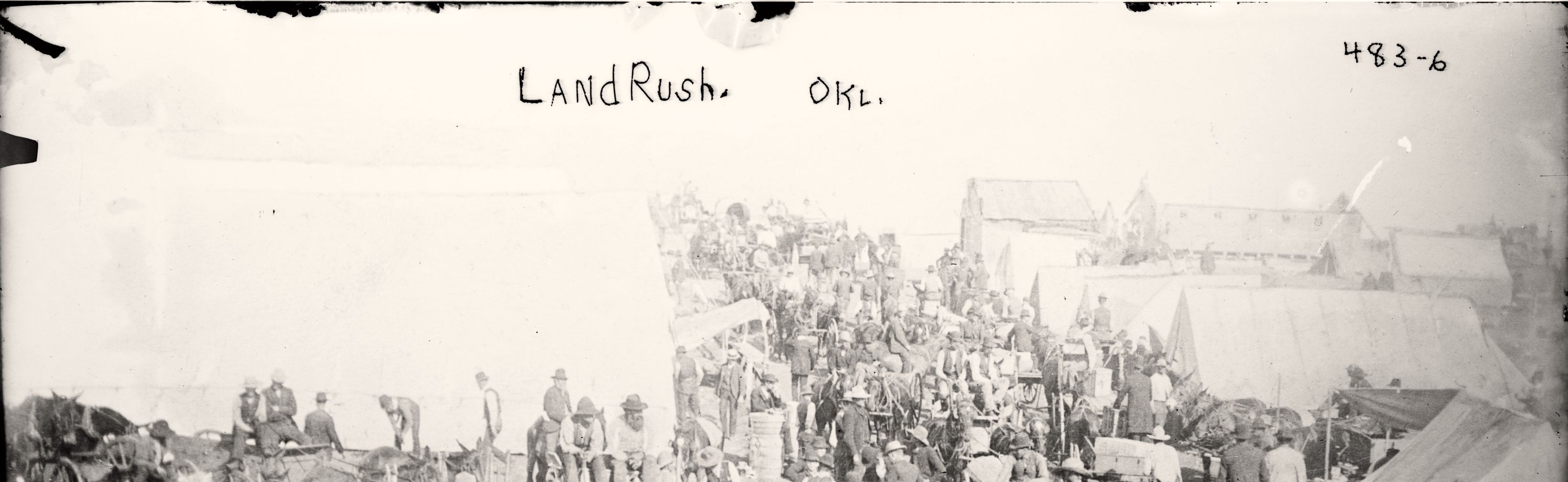 The top band of a glass plate negative: open sky with LandRush. OKL. handwritten across it, the file number 483-6, and the tents and wagons of a land rush camp along the bottom. Library of Congress ggbain.02286.